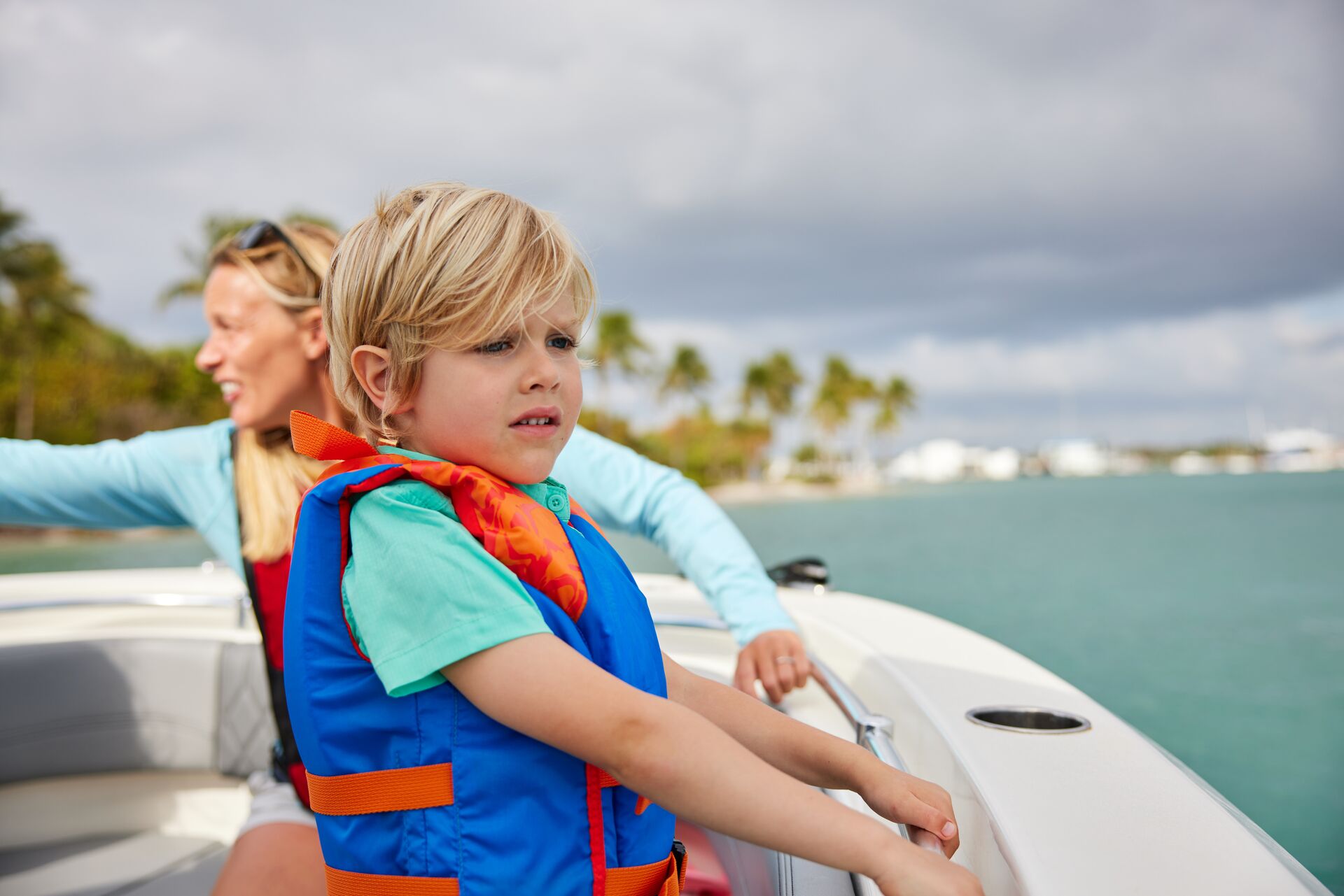 Child in life jacket at the side of a boat.