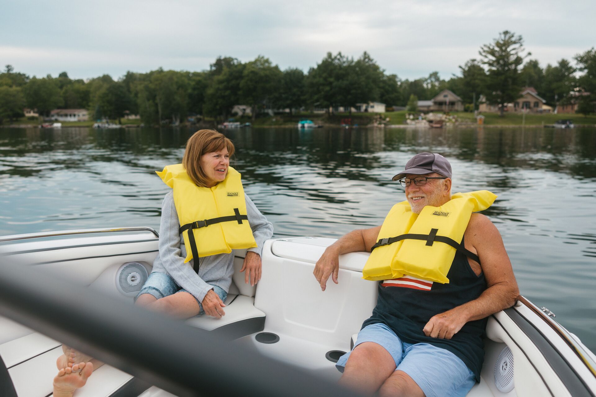Man and woman in yellow life vest smiling on a boat.