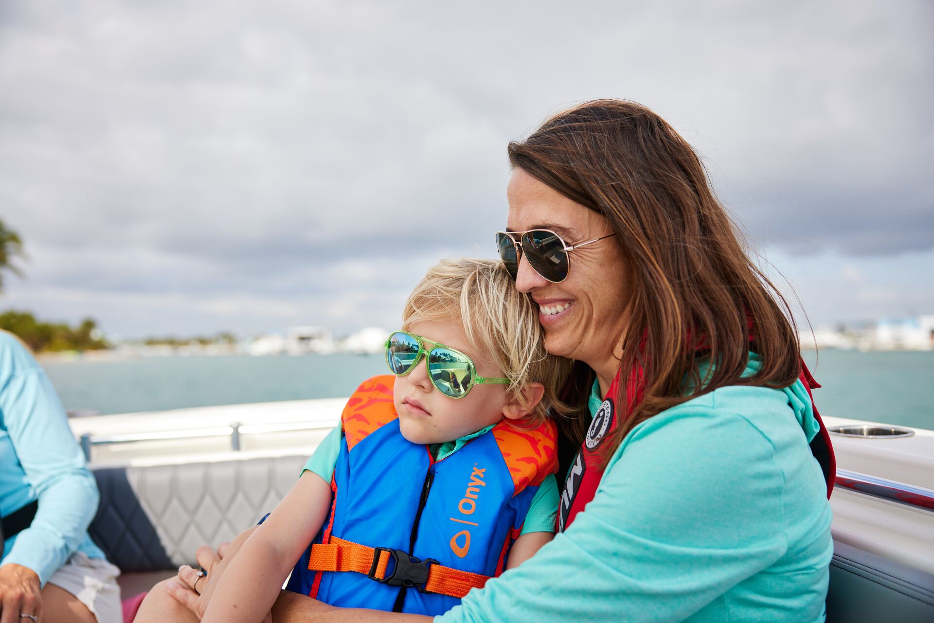Woman holds a child on her lap on a boat, how to stop seasickness concept.