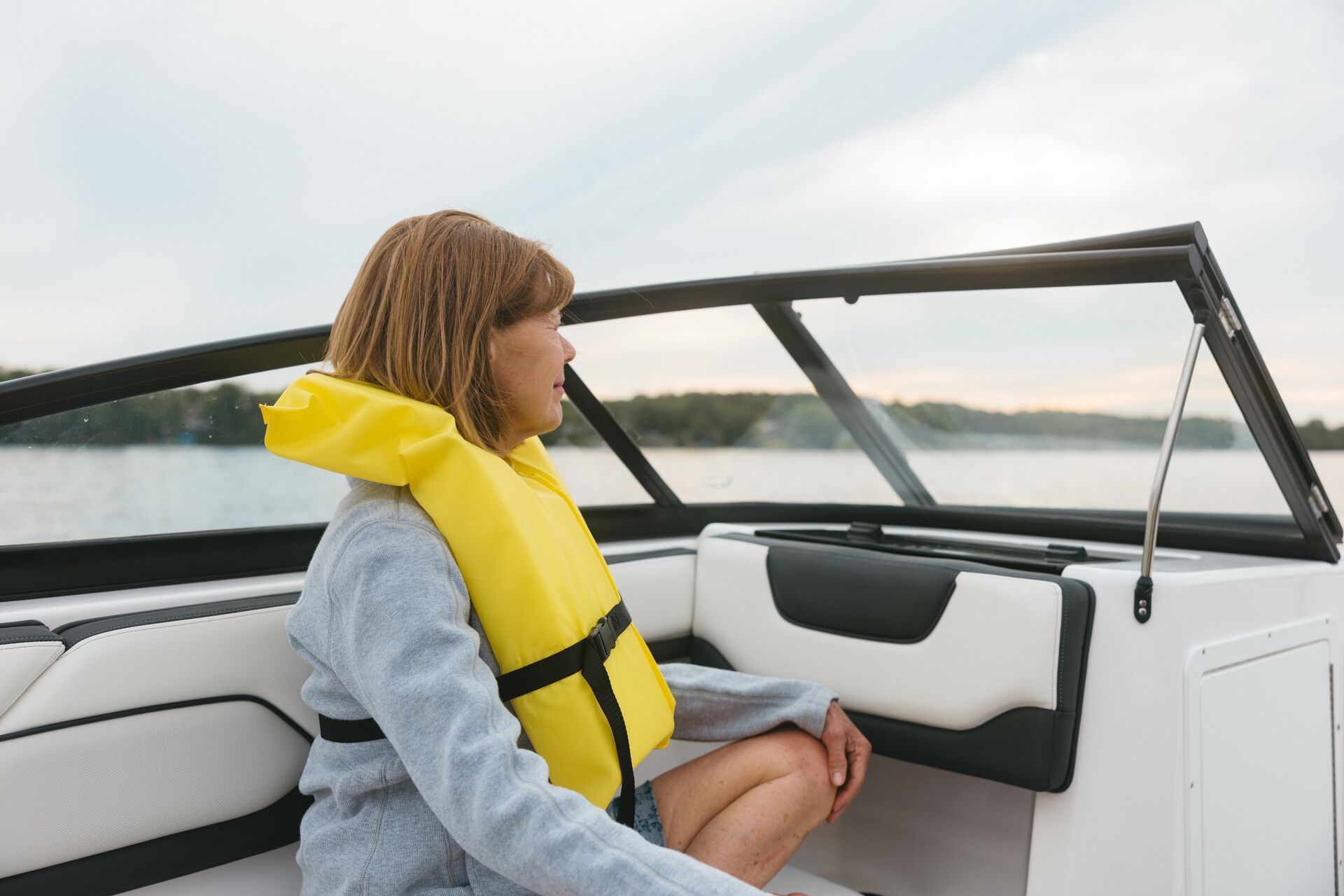 Woman on boat in yellow life jacket, how to avoid seasickness on a small boat concept.
