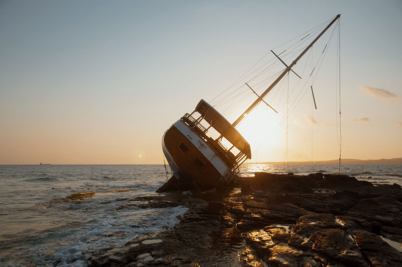 A sailboat sinks, how to survive a sinking ship concept. 