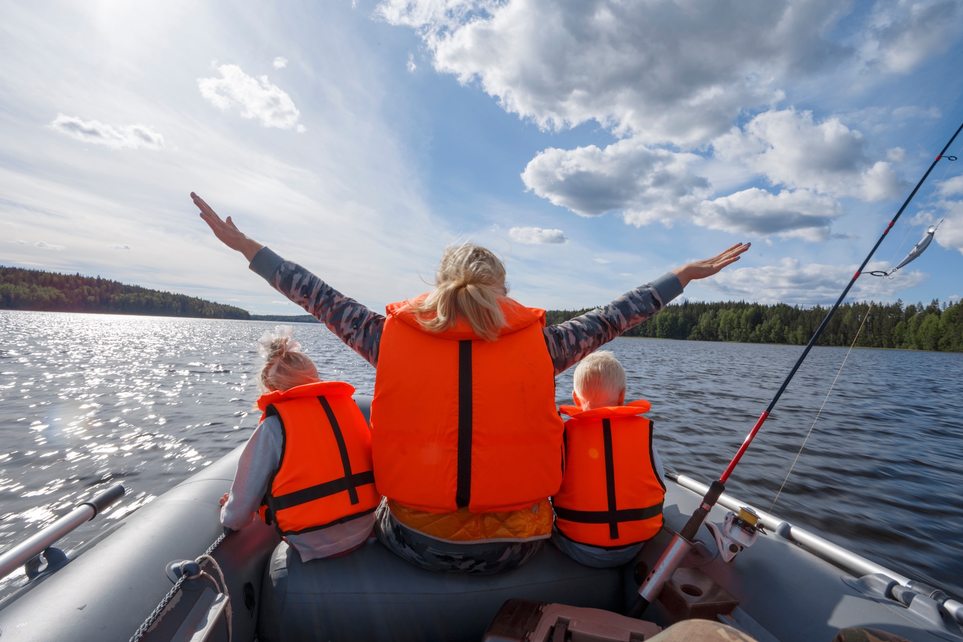 Woman and kids wearing life jackets in inflatable boat.