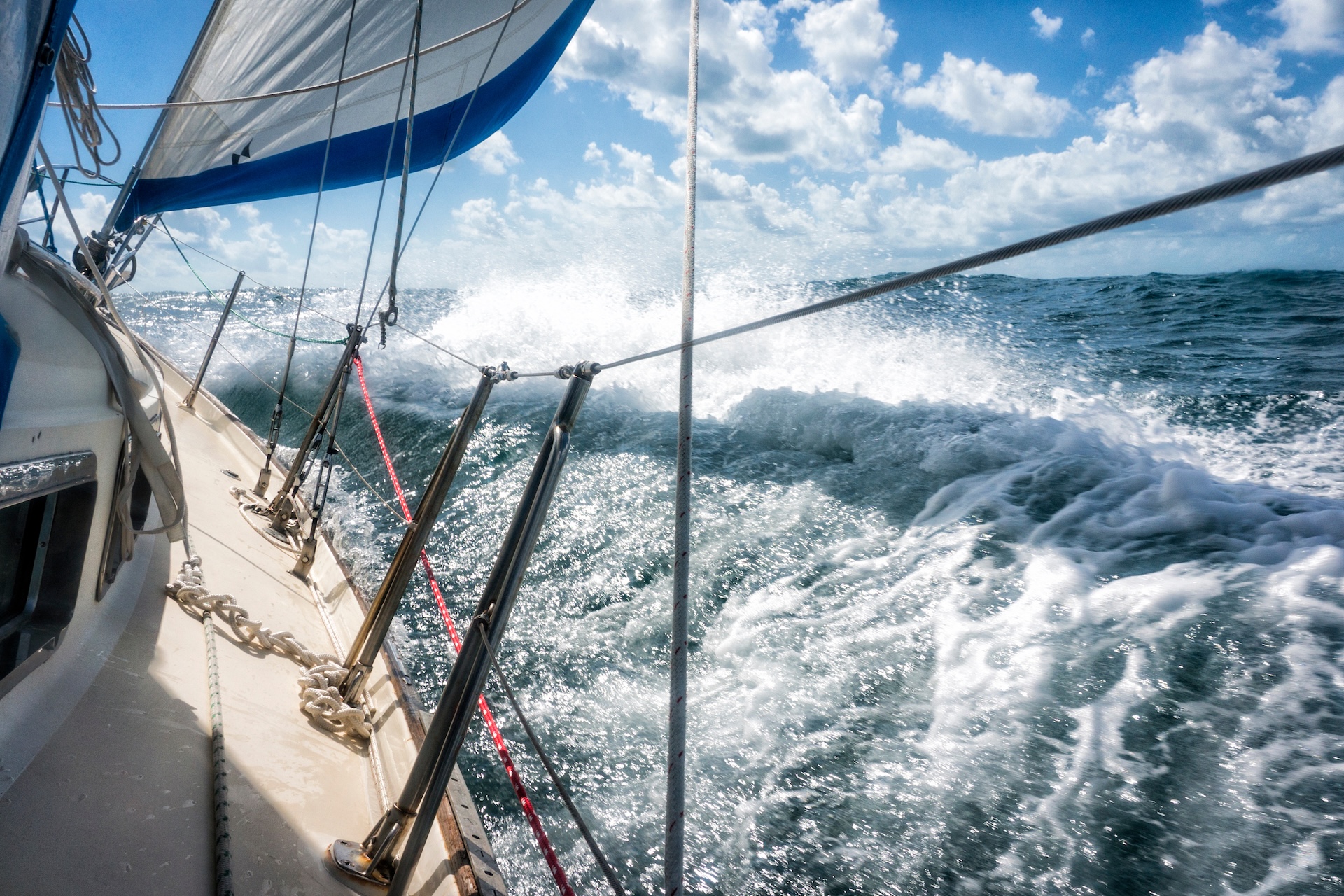 Sailboat navigating through waves, boats in rough seas concept.