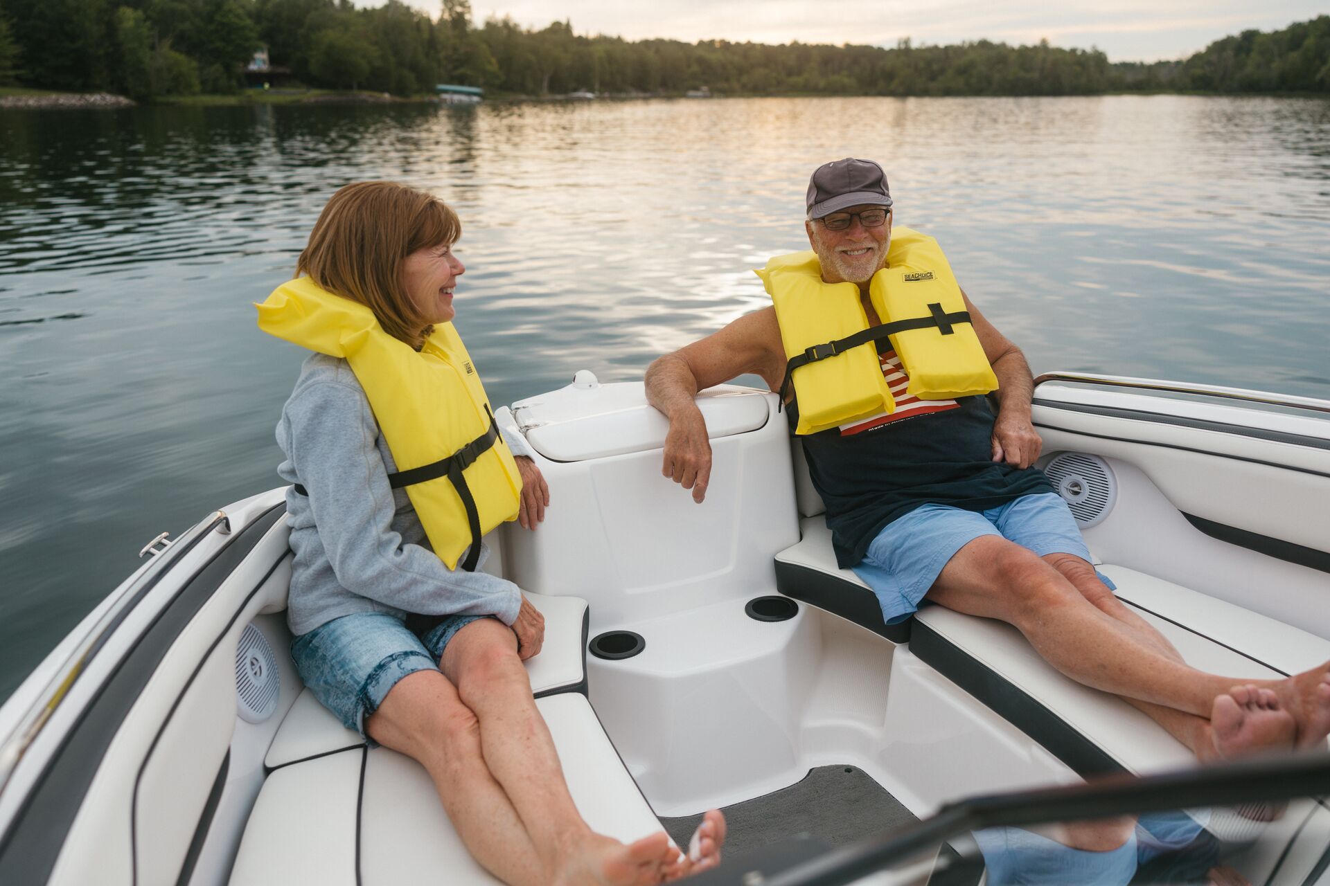Man and woman in yellow life vests relaxing in boat, Labor Day boat ride concept.