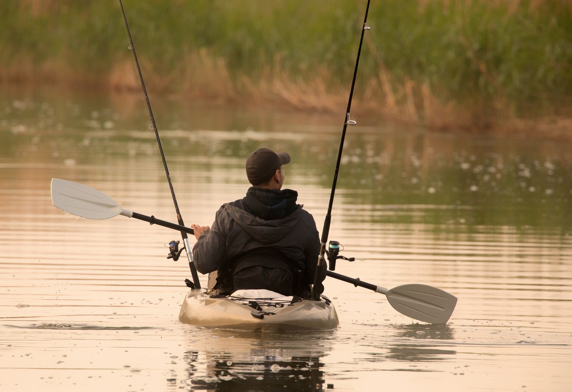Man in life jacket paddles fishing kayak, kayak life jacket concept. 