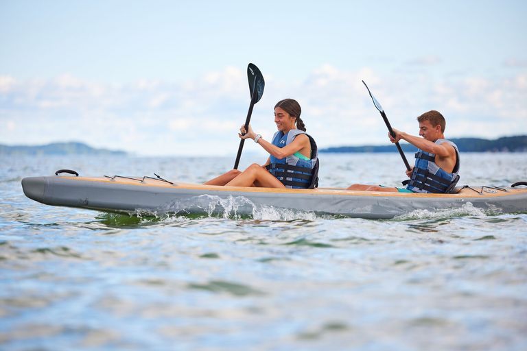 Two kids paddle a kayak, do you have to wear a lifejacket on a kayak concept. 