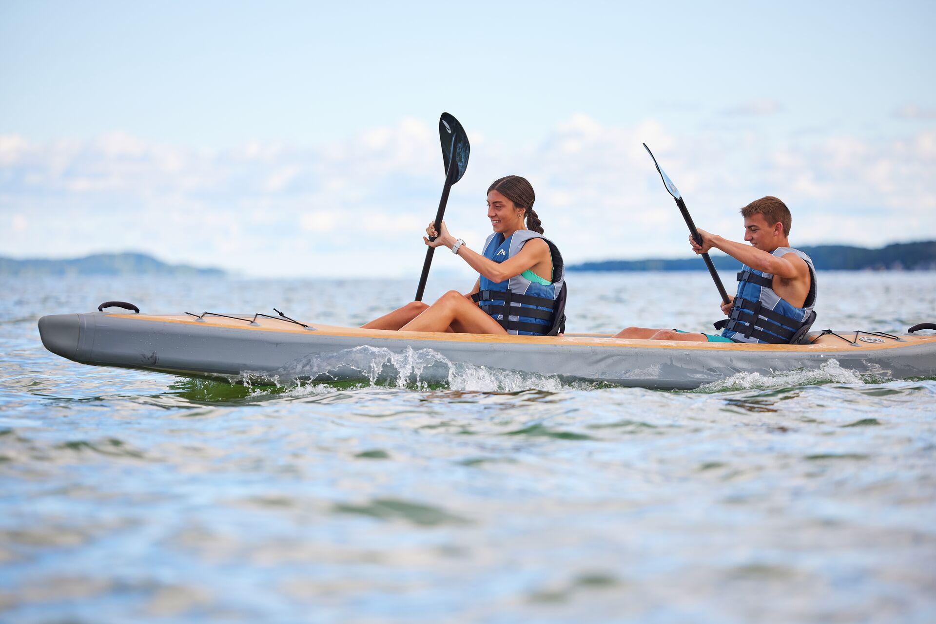 Two kids paddle a kayak, do you have to wear a lifejacket on a kayak concept. 