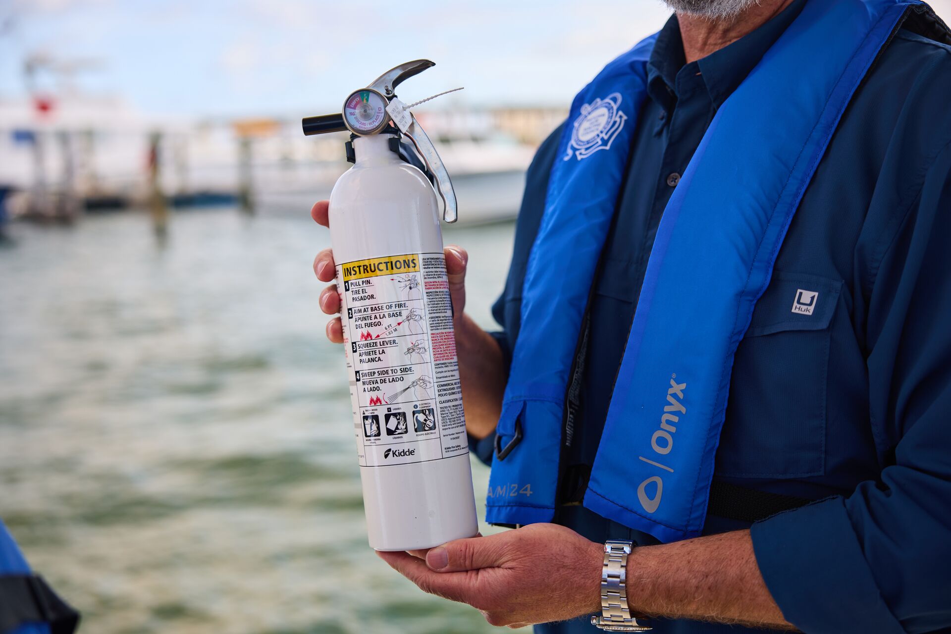 Man holds fire extinguisher on boat, boating safety equipment concept.