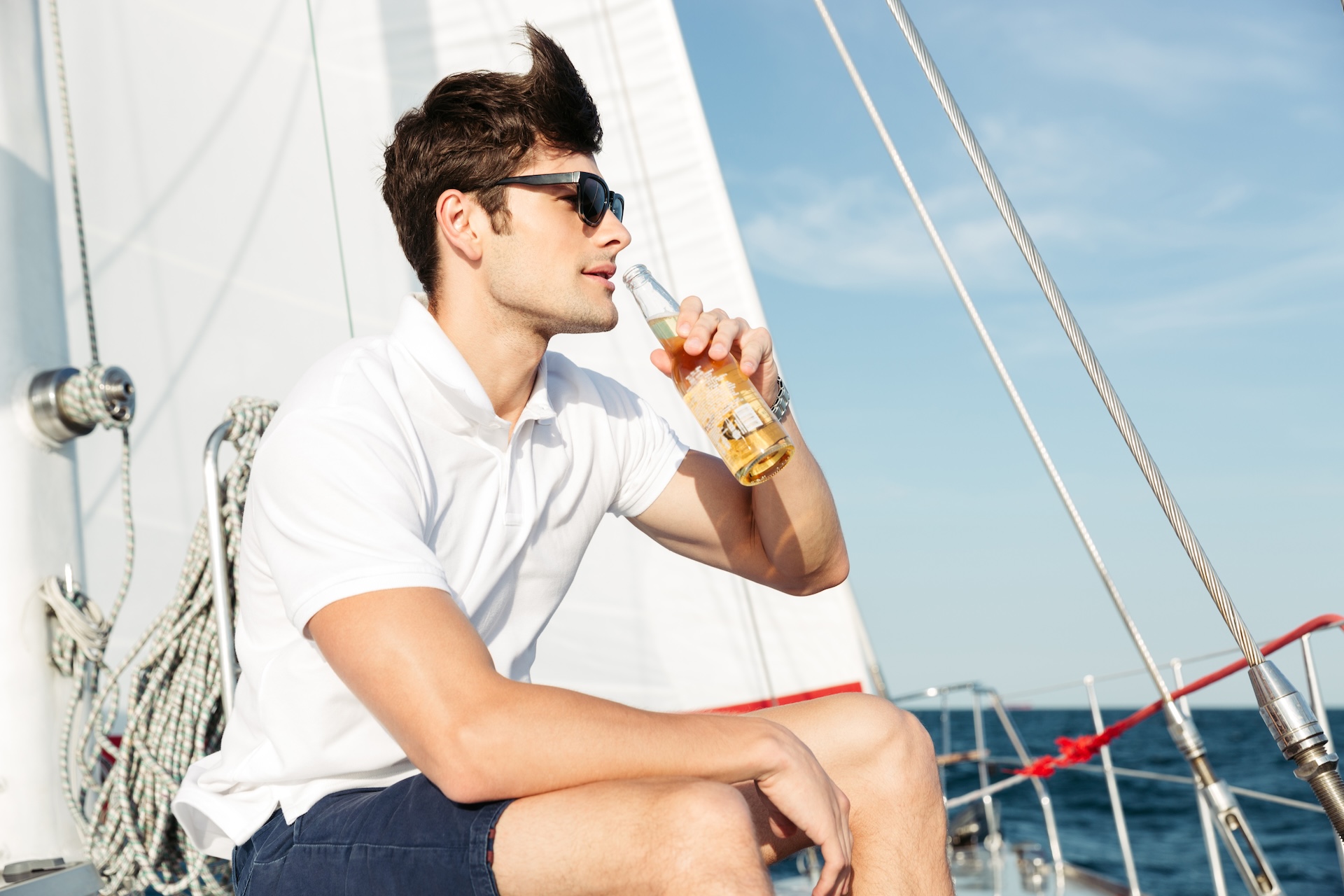 Man drinks from bottle of beer on boat, causes of boating accidents concept.