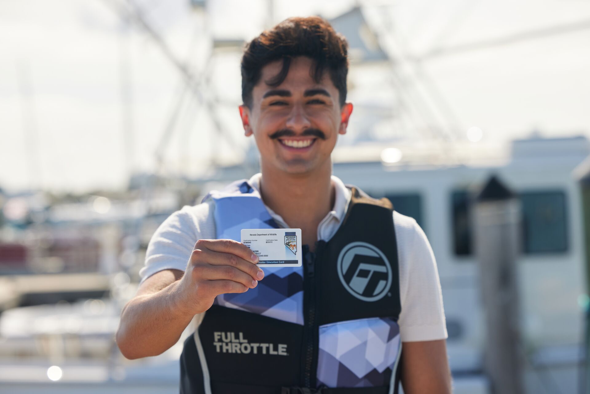 Man smiles and holds boater education card, learn to prevent boating accident injuries concept.