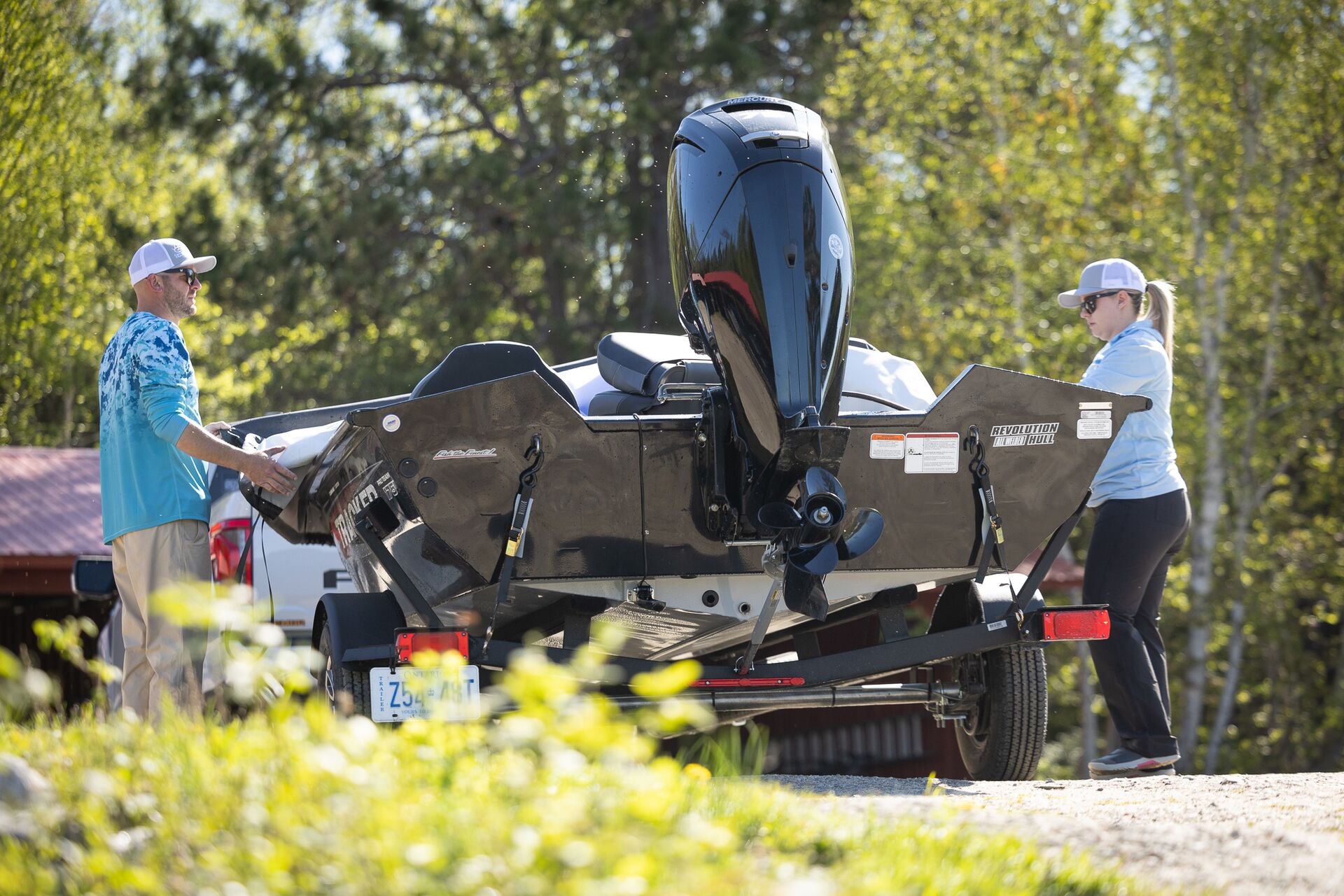Man and woman next to boat on trailer, towing capacity calculator boats concept.