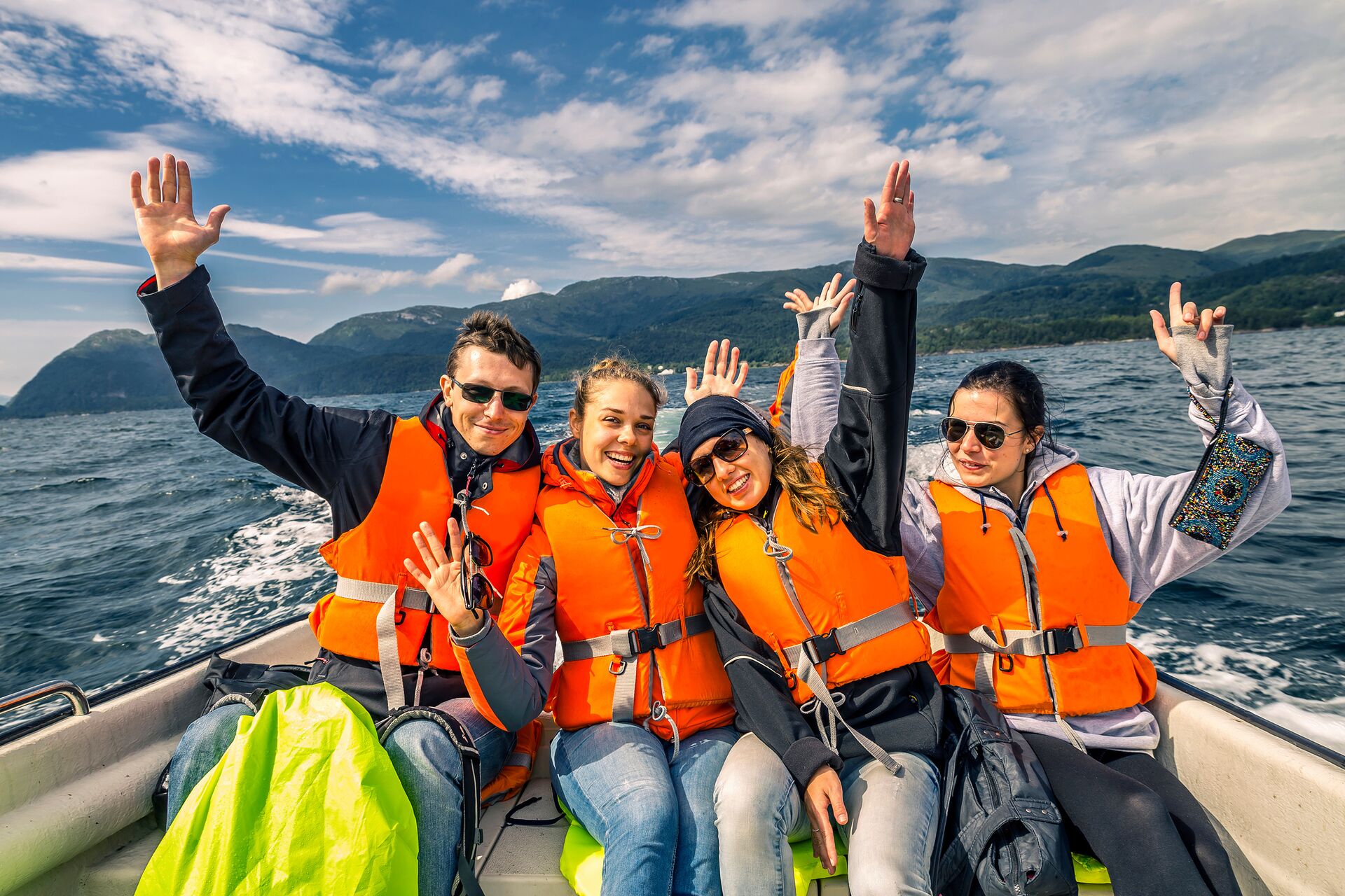 Four people in back of boat in orange life vests, maximum boat capacity rules concept.