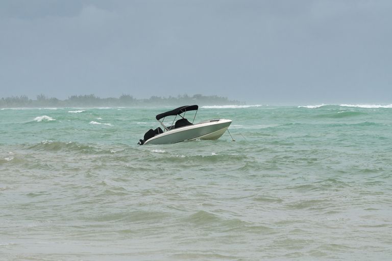 Small boat anchored in rough water, boating weather warnings concept. 