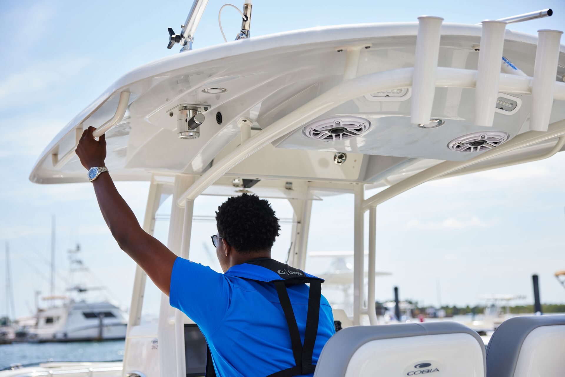 Back view of a man in blue shirt and life vest driving a boat, learn common boating words concept. 