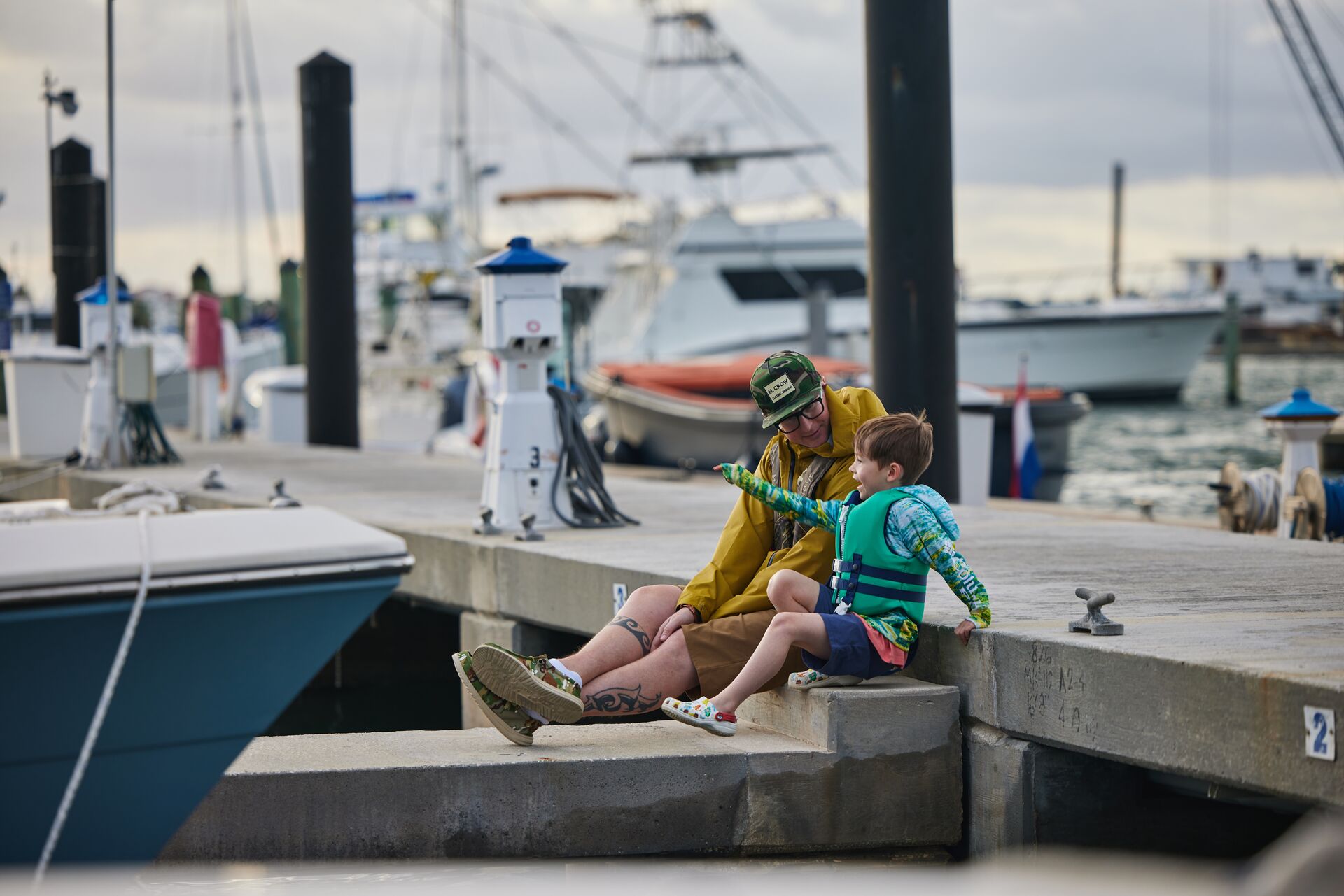 Man and boy in life jackets on dock, learning boat terms concept. 