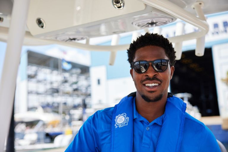 Smiling man in sunglasses and blue shirt on boat, get a boat safety certification concept.