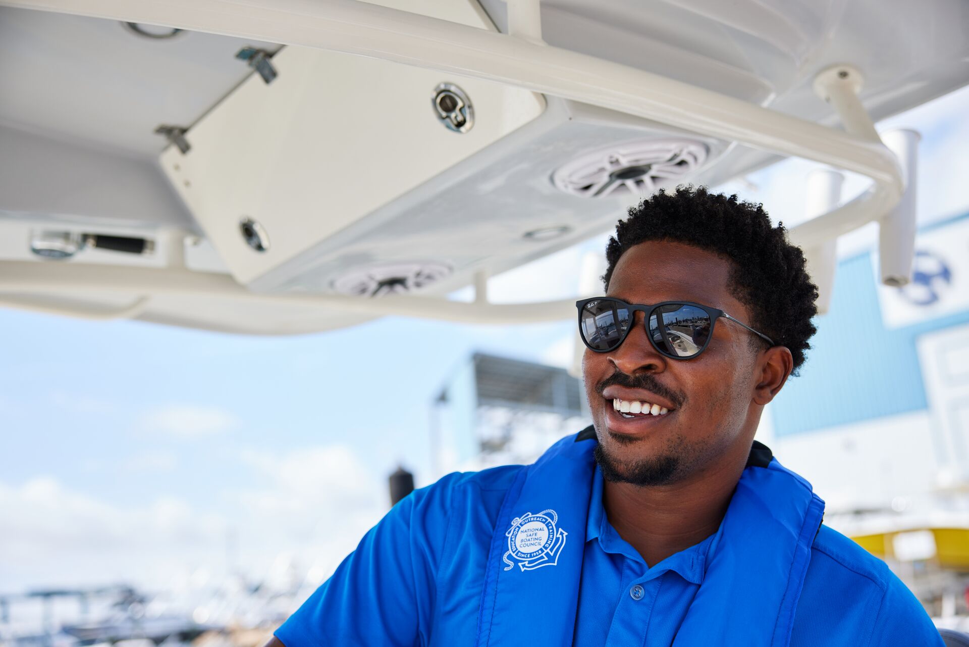Smiling man wearing blue shirt on boat. 