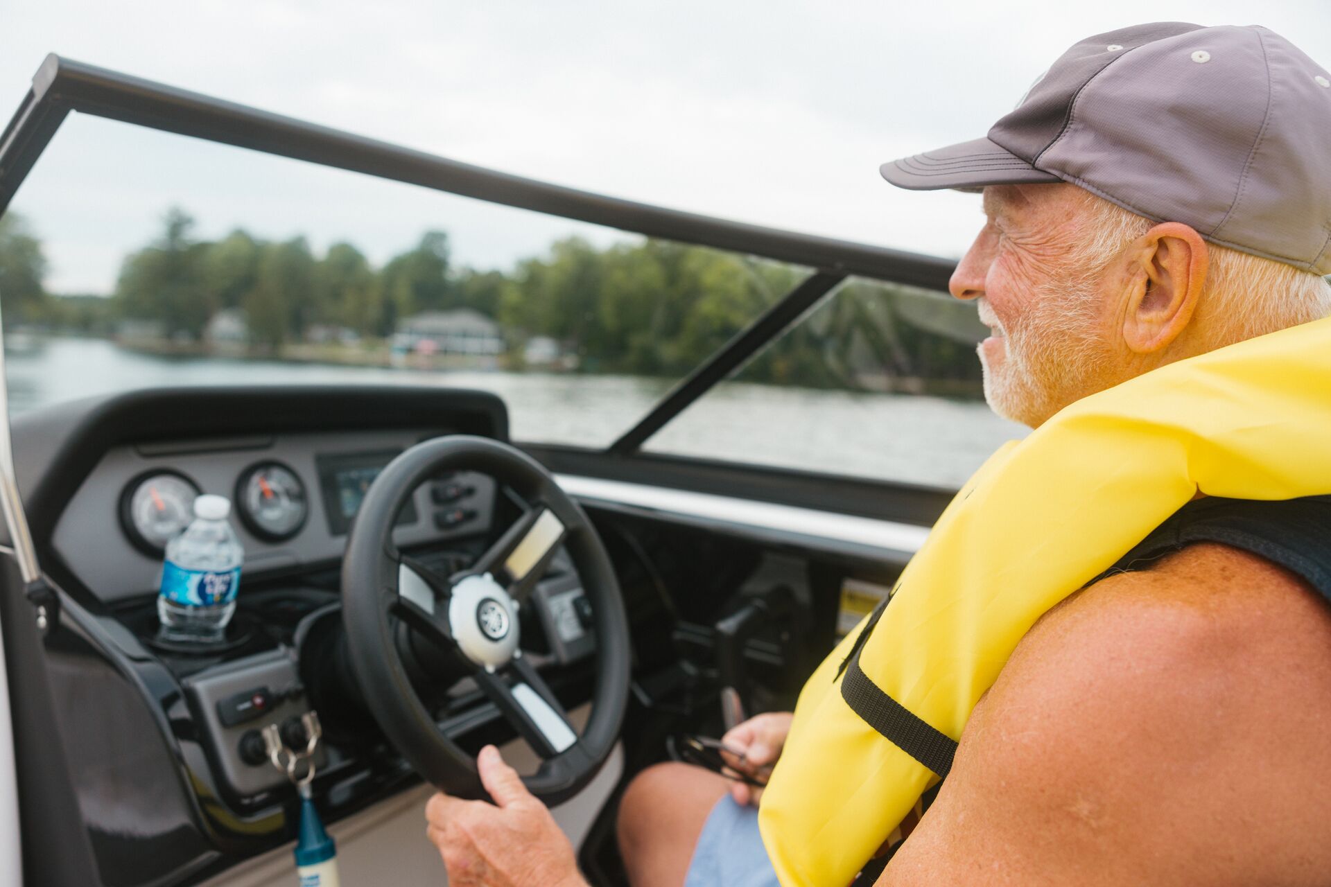Close-up of man in yellow life vest driving boat, get a Sask boat license concept. 