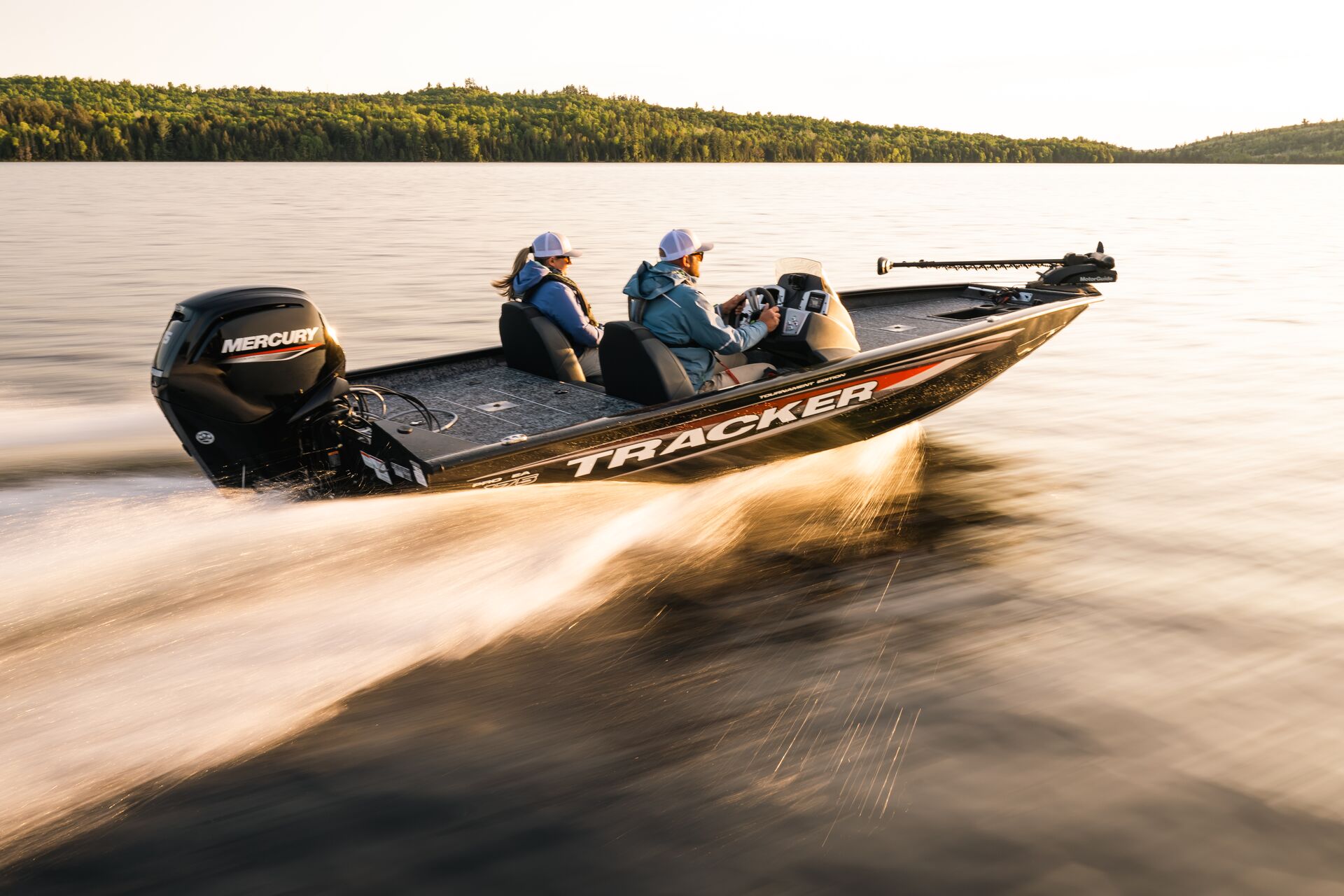 Two people in fast moving black bass boat. 