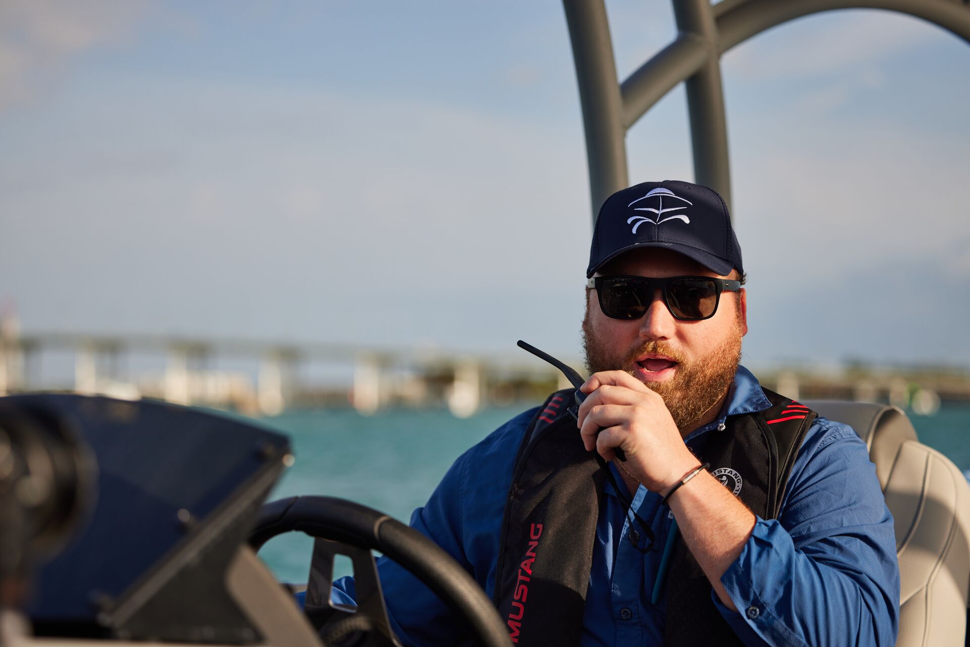 Boat operator uses a boat radio while at the helm. 