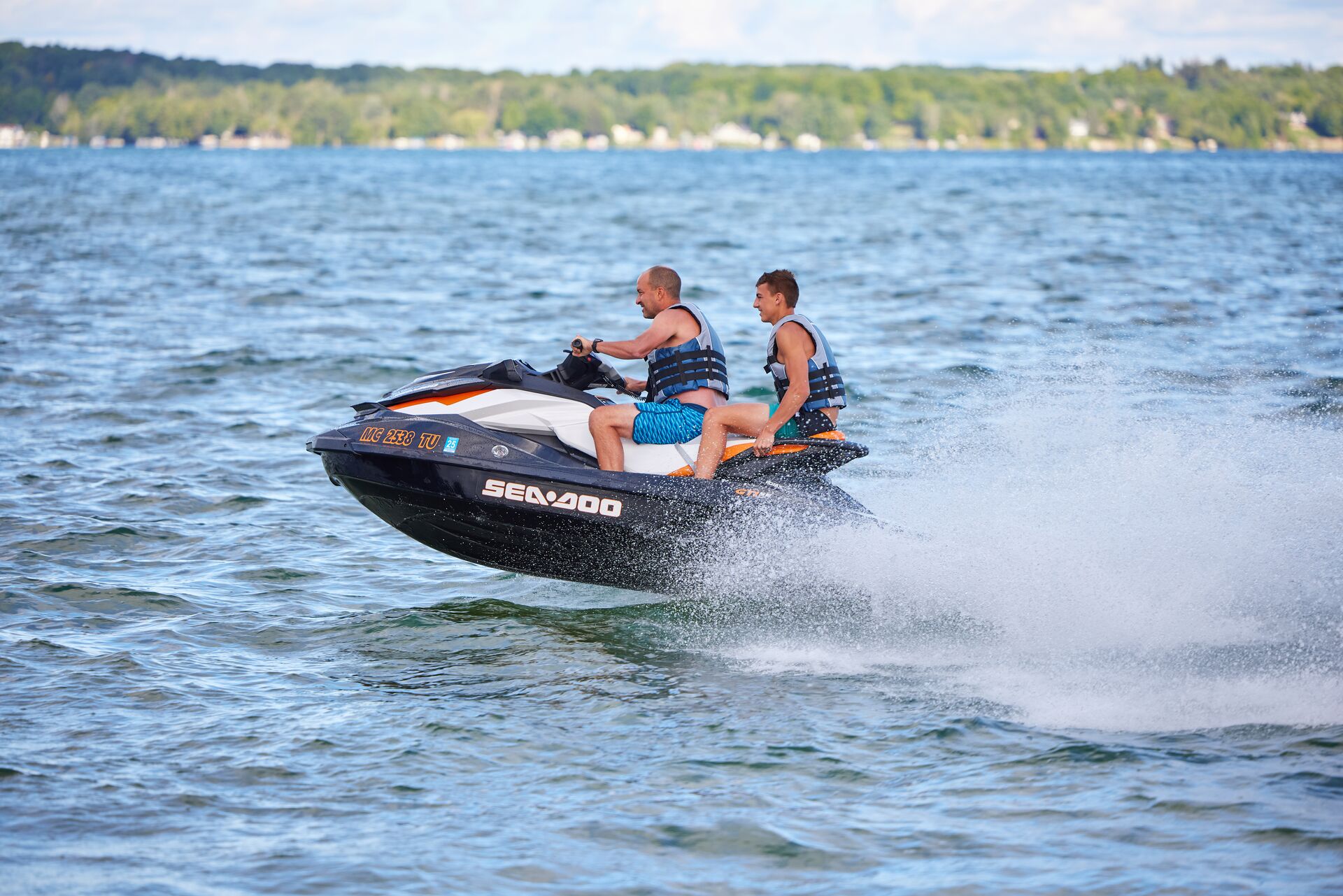 Two guys on a jet ski on the water.