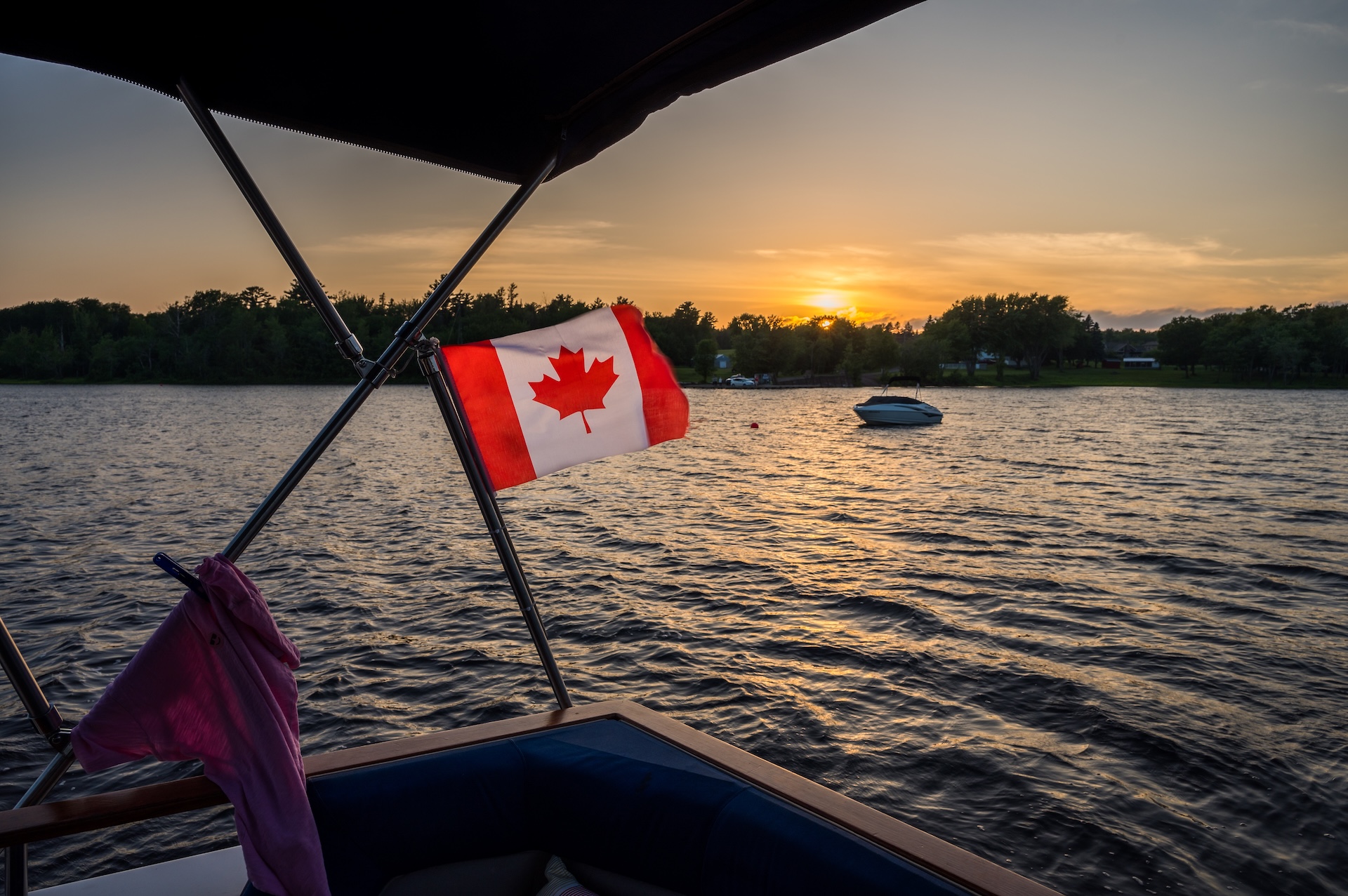 Canadian flag on a boat flies over the water. 