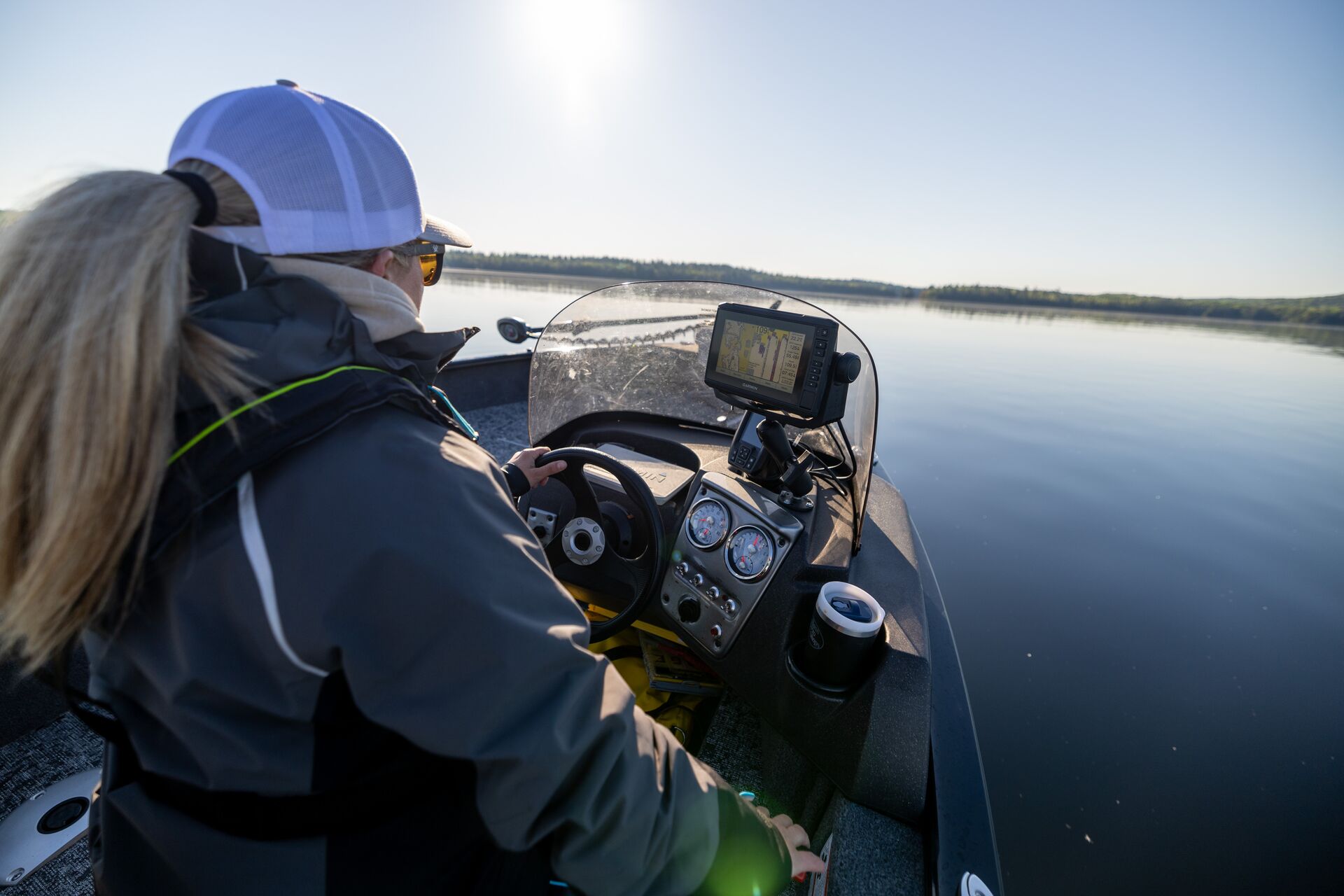 Over the should view of woman driving boat, Ontario boating license concept. 