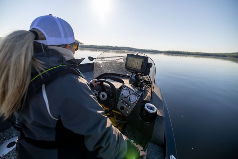Over the should view of woman driving boat, Ontario boating license concept. 