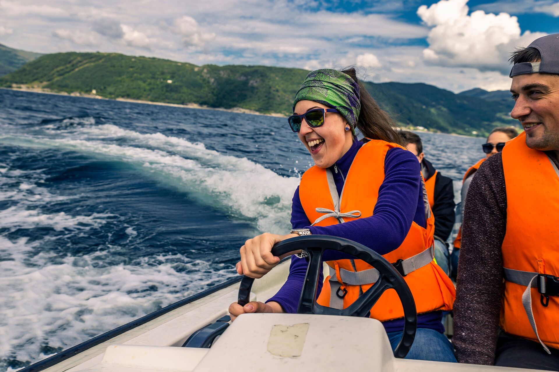 Smiling woman and man in orange life vests drive boat, take the Canadian boating license test concept.