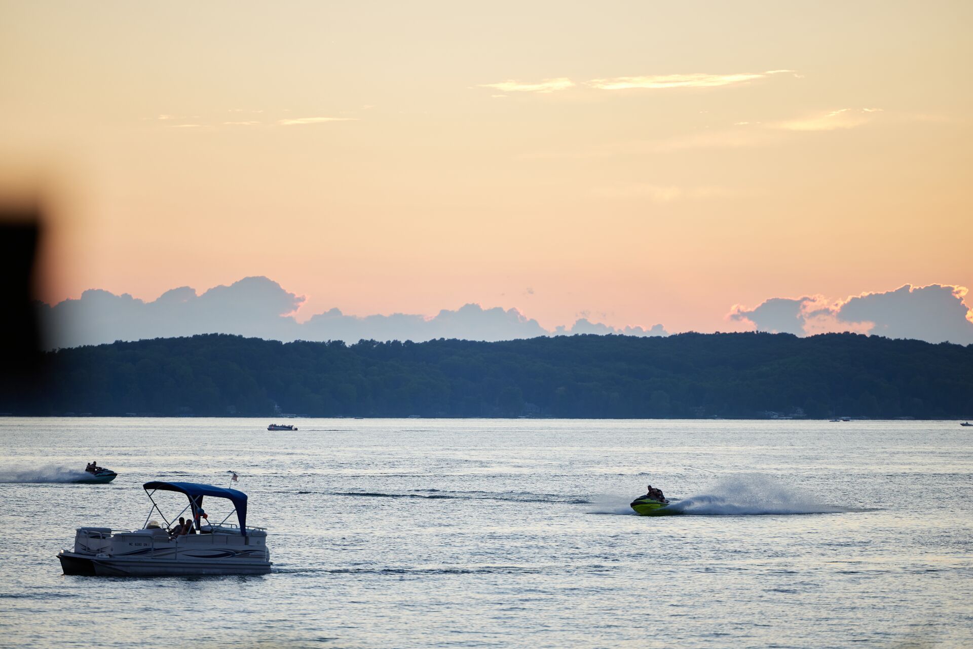 Jet ski and boat in the distance on lake, boating license for jet ski in Alberta concept. 