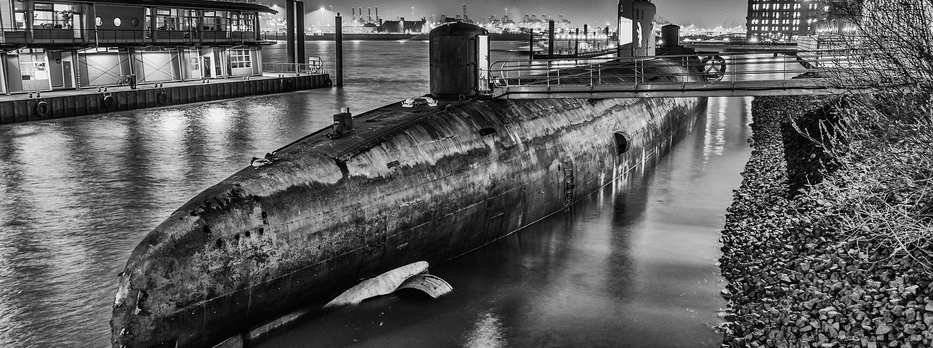 A photo of a submarine in the water near land. 
