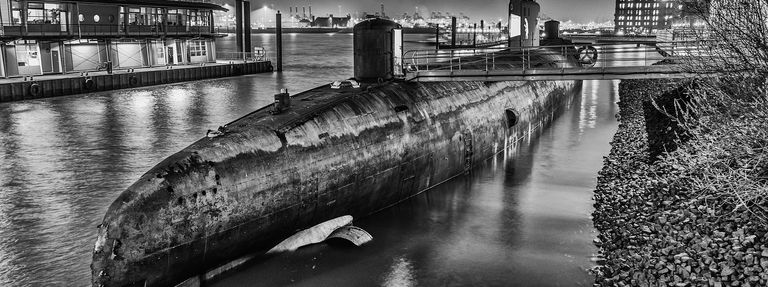 A photo of a submarine in the water near land. 