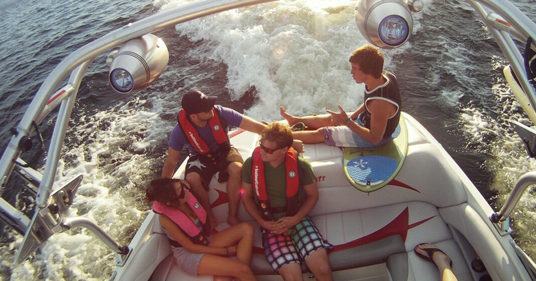 Four people sit in back of boat, fine for no boating license Canada concept. 