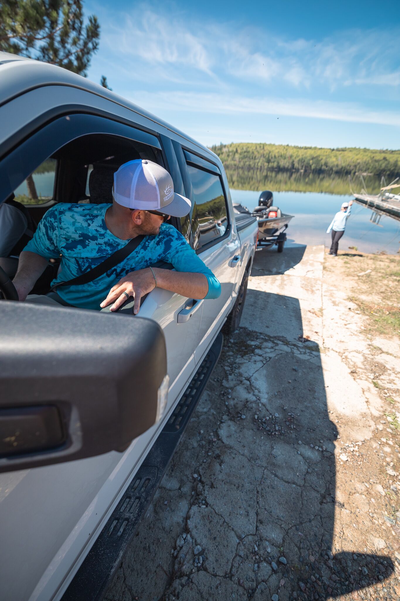 Man in truck backs boat on trailer into water, avoid boating fines Canada concept.