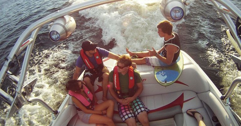 Four people sit in back of boat, fine for no boating license Canada concept.
