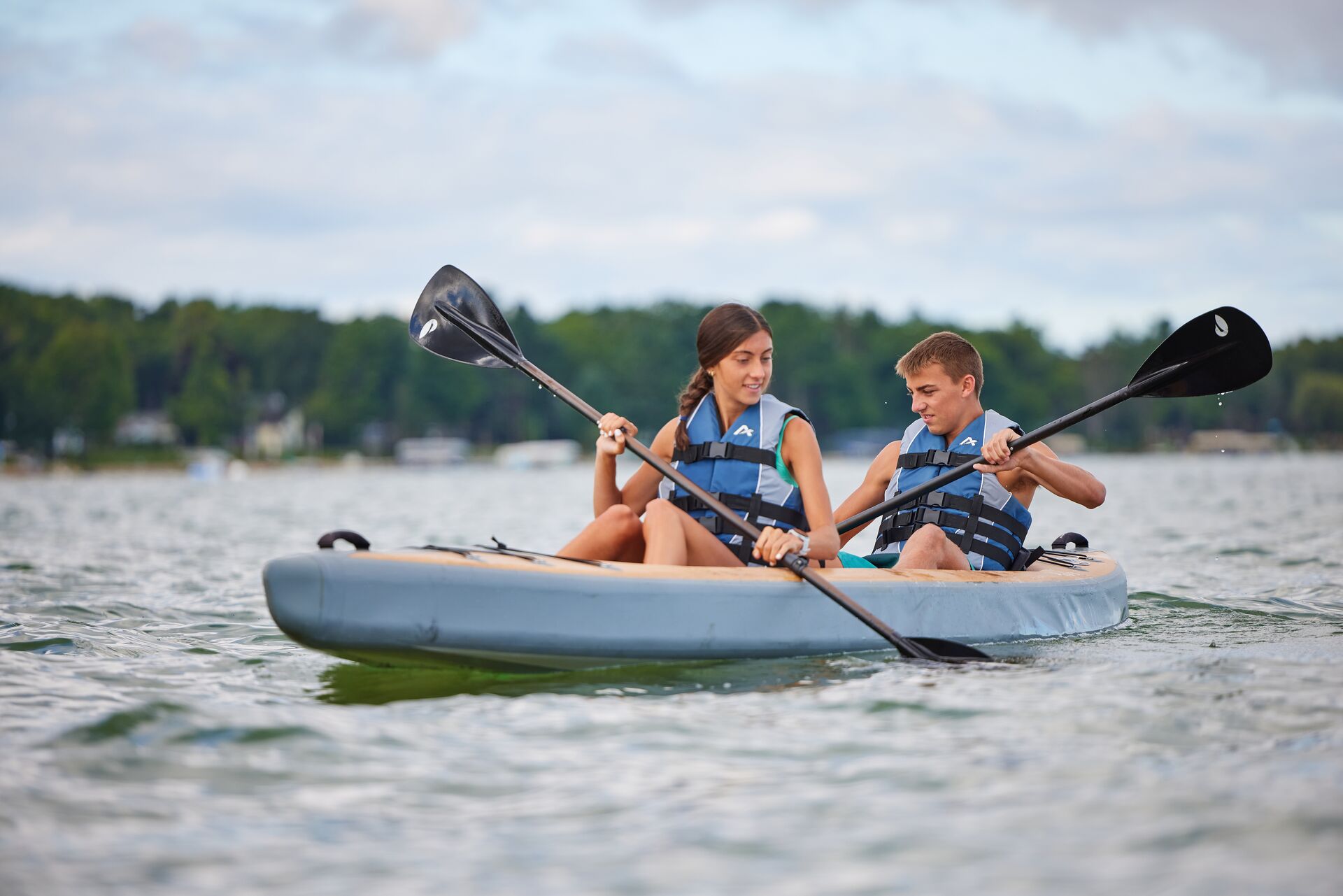 Girl and boy in lifejackets paddle kayak, do you need a licence for a kayak concept.