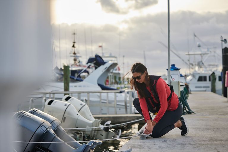 Woman ties rope to dock, take the boater exam Canada concept. 