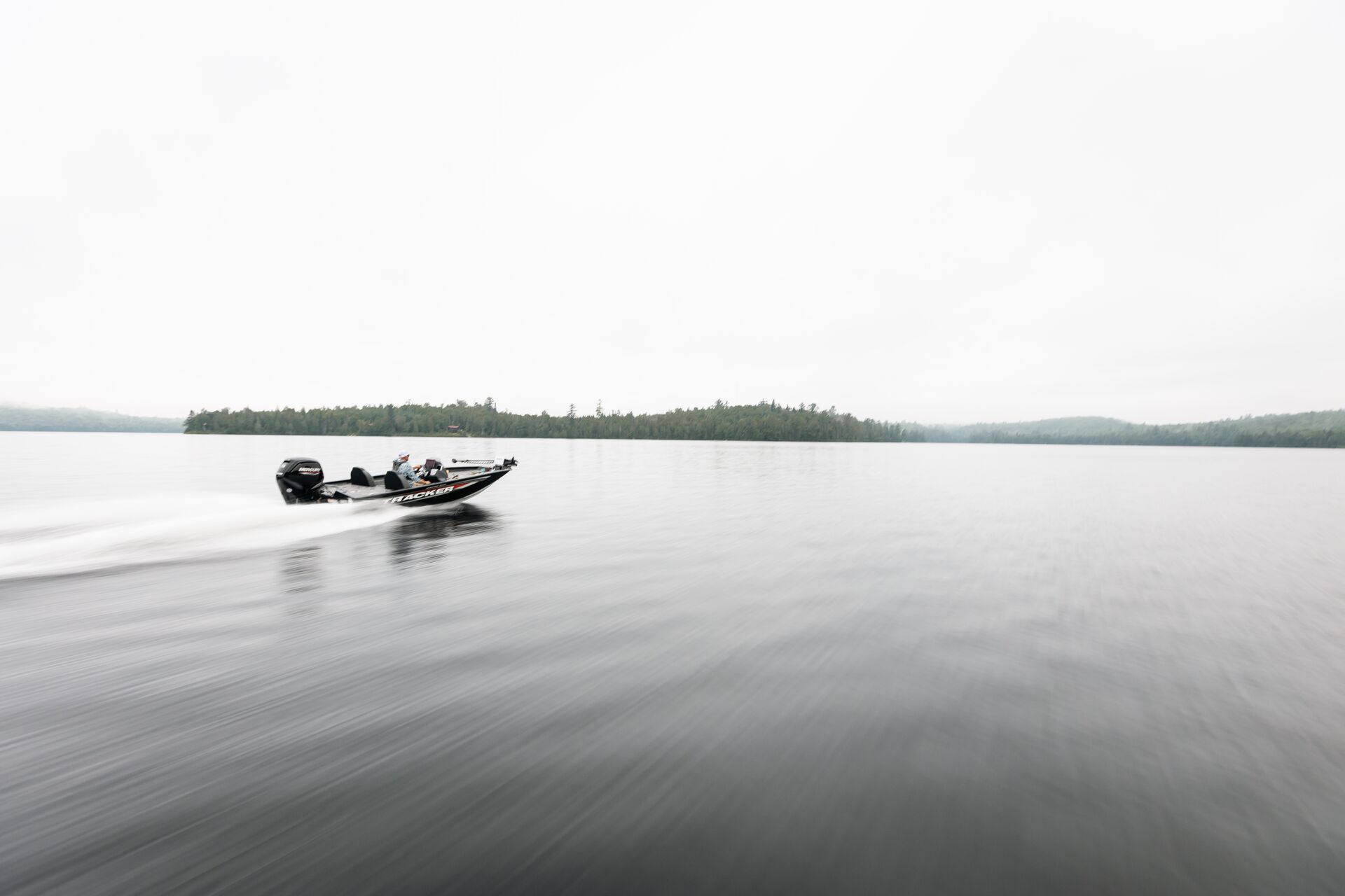 Bass boat moving on a lake in the distance, Pleasure Craft Licence renewal concept. 