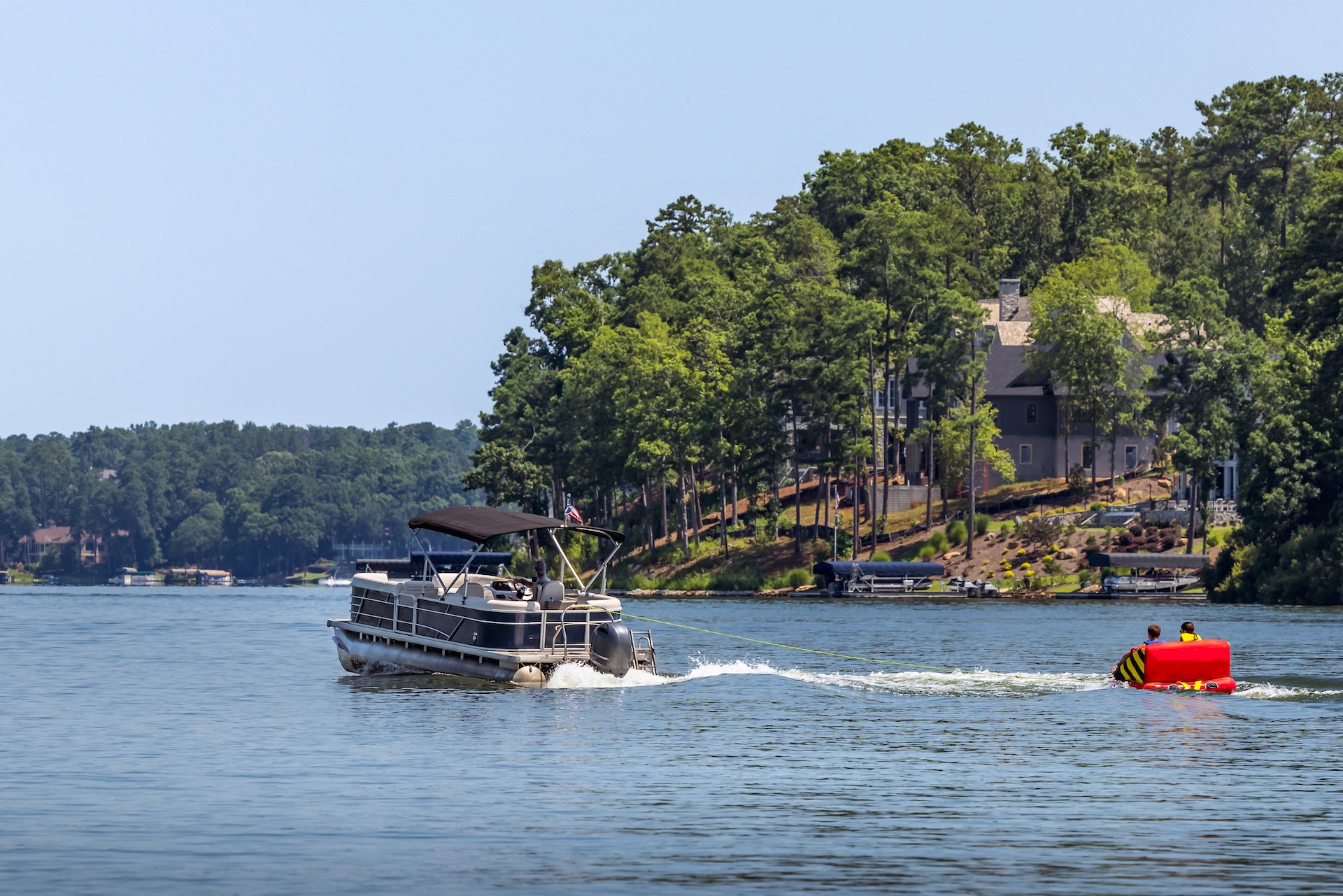Pontoon boat pulls people on inflatable, renew your Pleasure Craft Licence concept. 