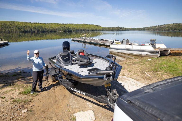 Woman directing boat on trailer into water, Pleasure Craft Licence renewal concept.