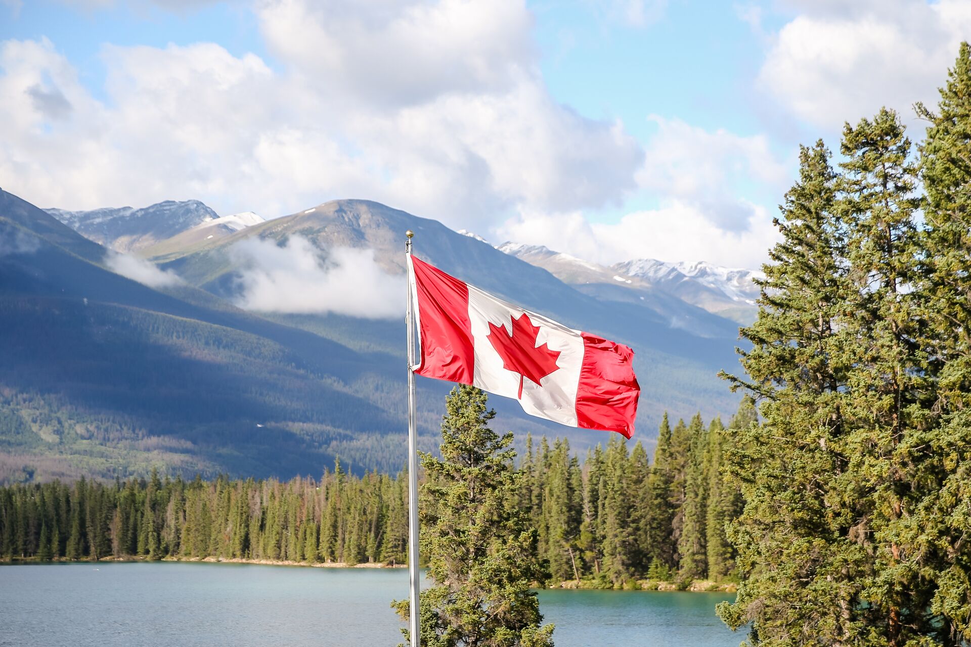 Canadian flag flies over a lake, do Americans need a boating license in Canada concept.