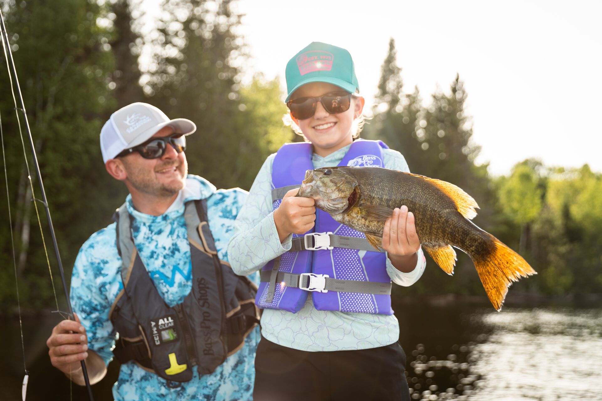 Girl holding fish with man nearby, fishing licence Canada concept.