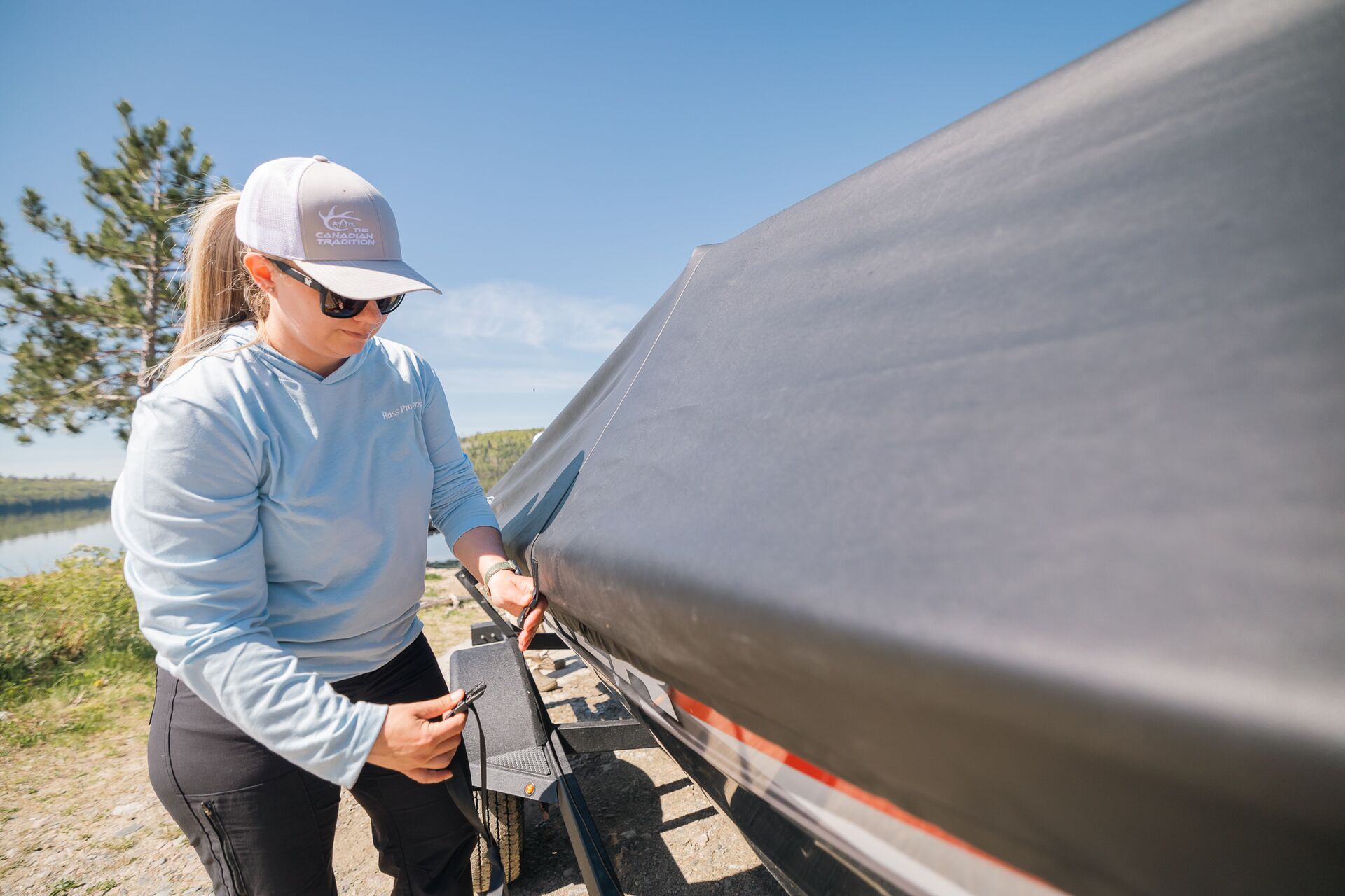 Woman attaches a cover to a boat, winterizing a boat concept.