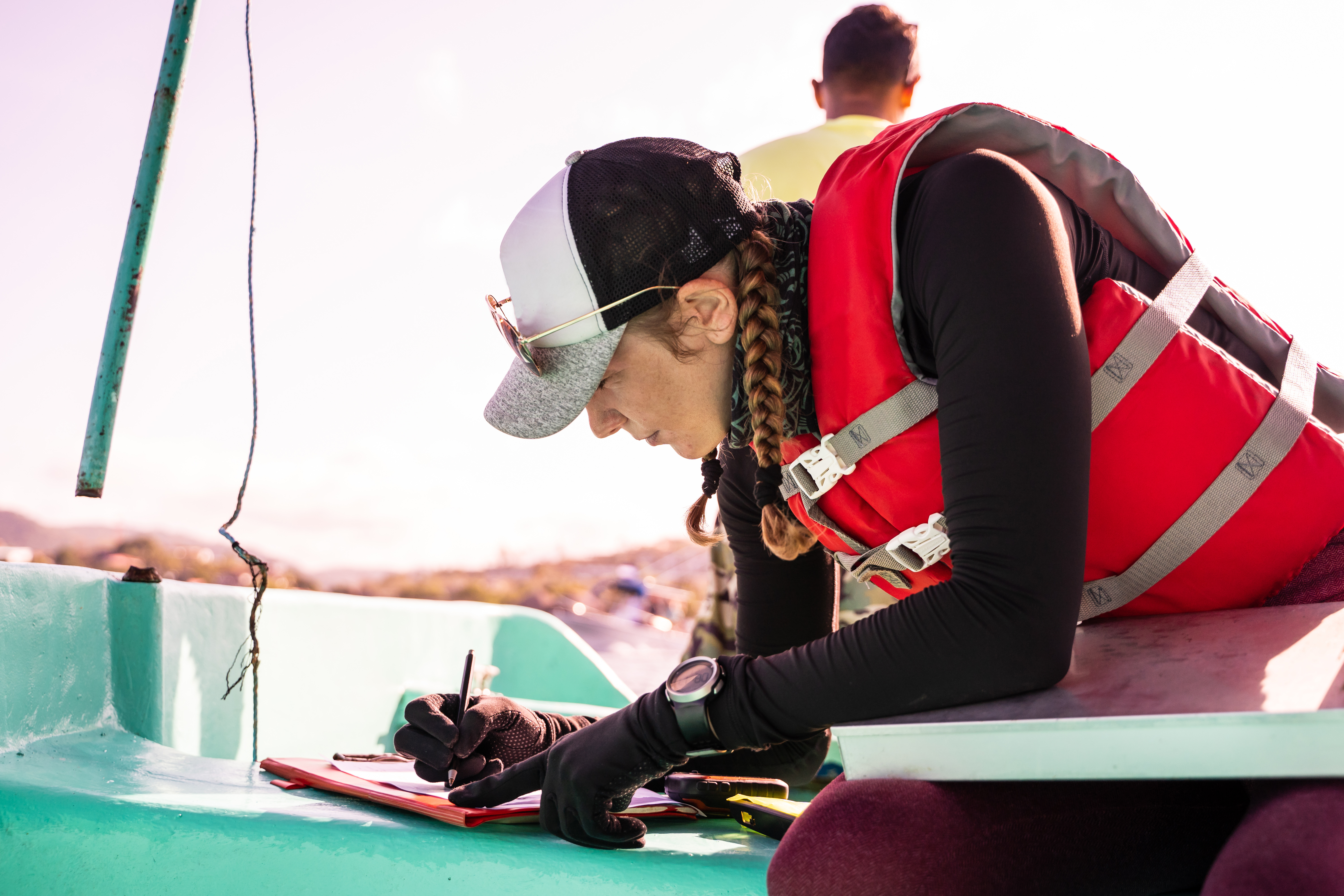 A woman reviews a checklist while wearing life jacket on a boat. 