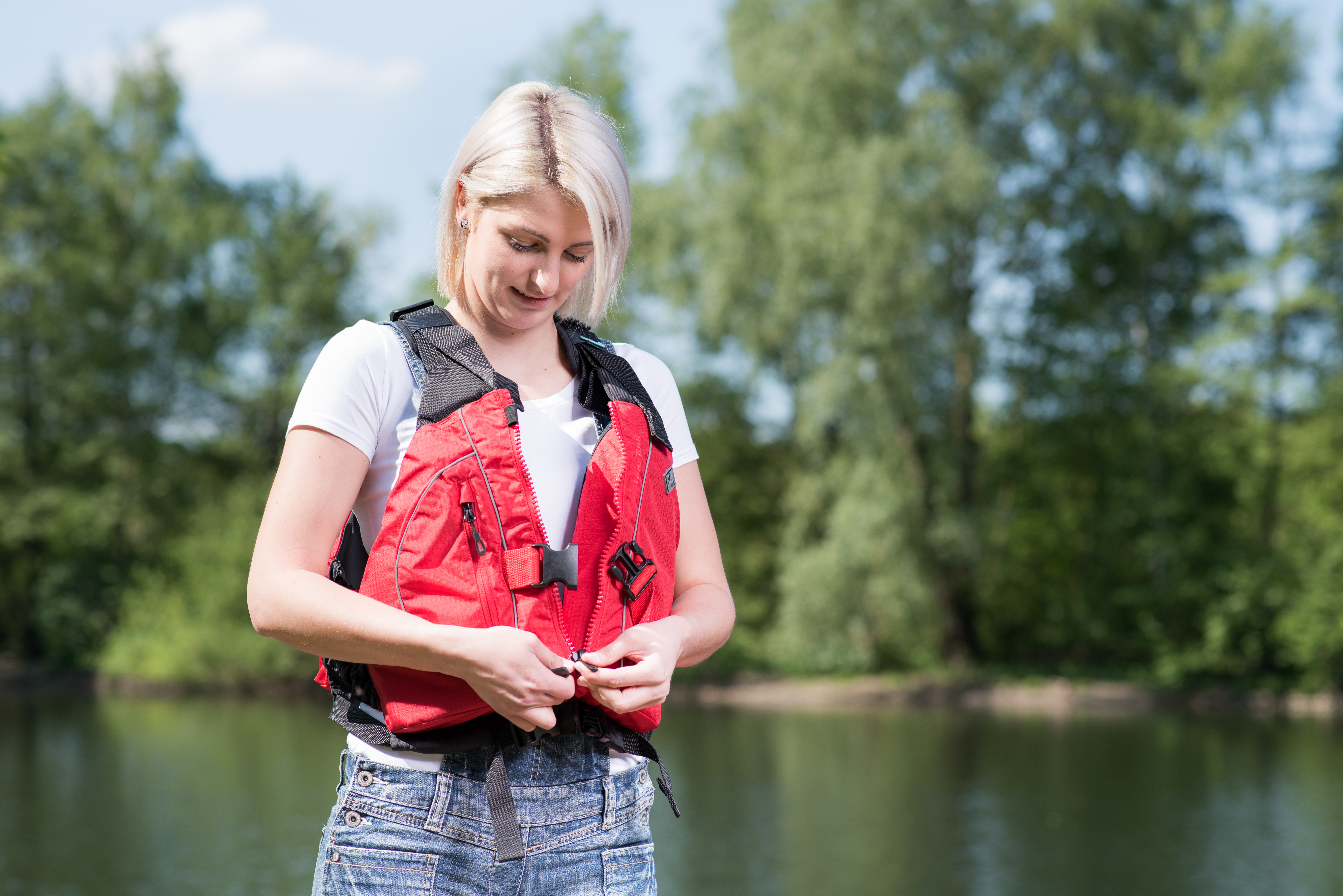 A woman fastens a lifejacket to find the right fit. 