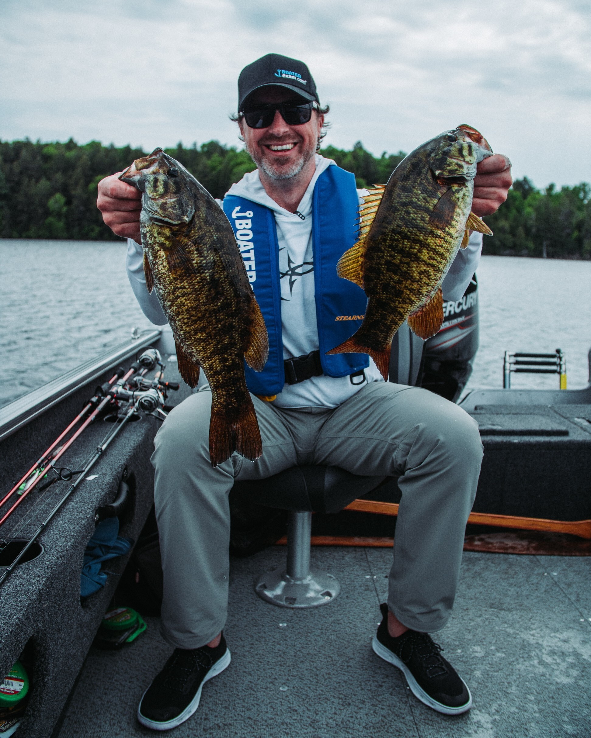 A man holding two fish in a boat, bass fishing concept. 