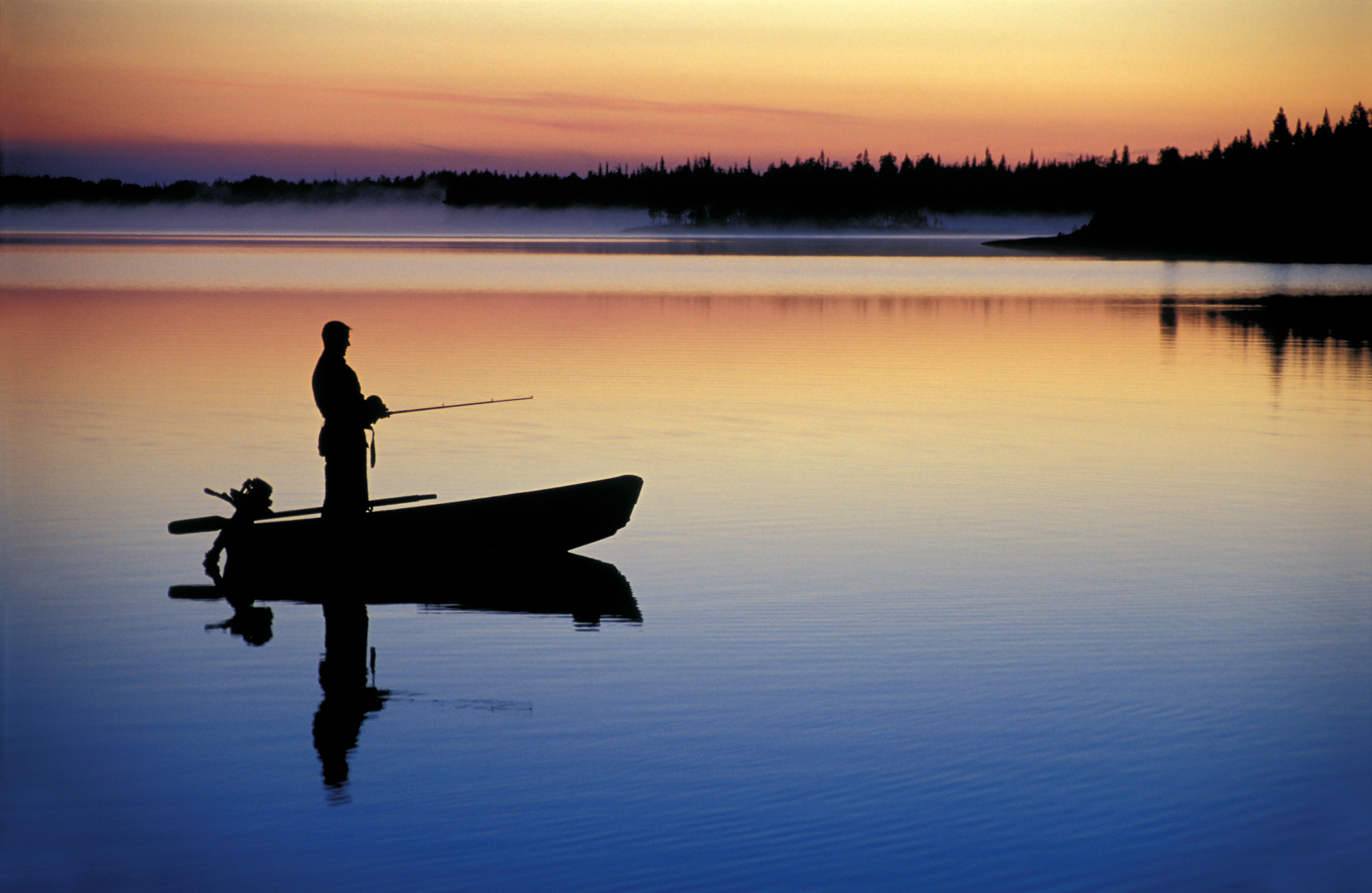 A person fishing from a boat in the distance, bass fishing concept. 