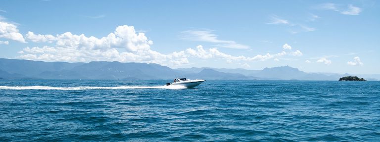 A motorboat races on the water in the distance, avoid boating accidents concept. 