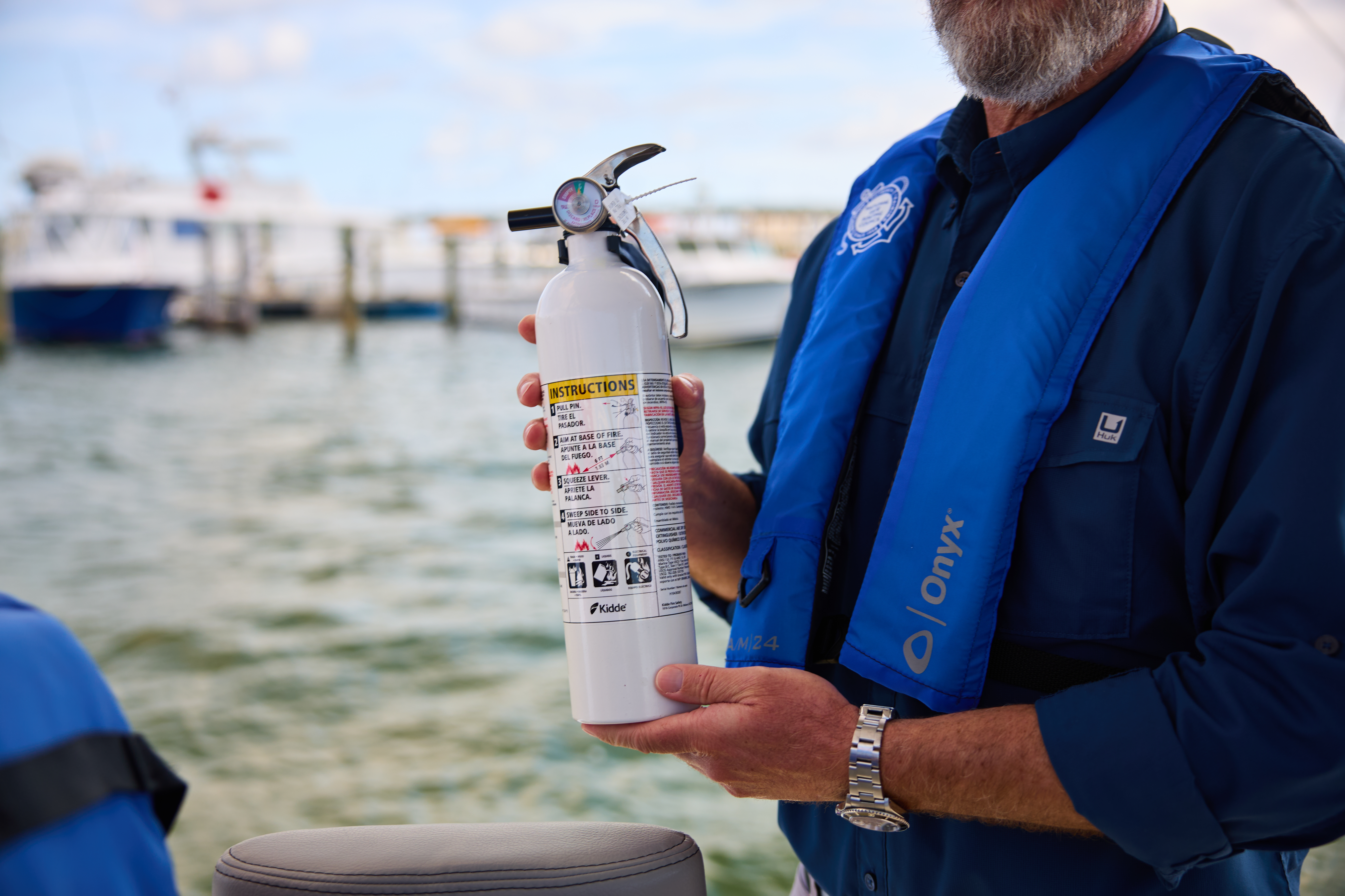 Close-up of a person holding a fire extinguisher on a boat, Quebec boating license concept. 