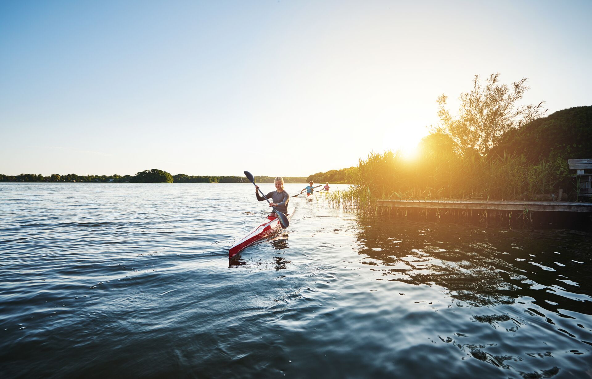 People kayaking around the edge of a lake, canoe vs boat life jackets concept. 